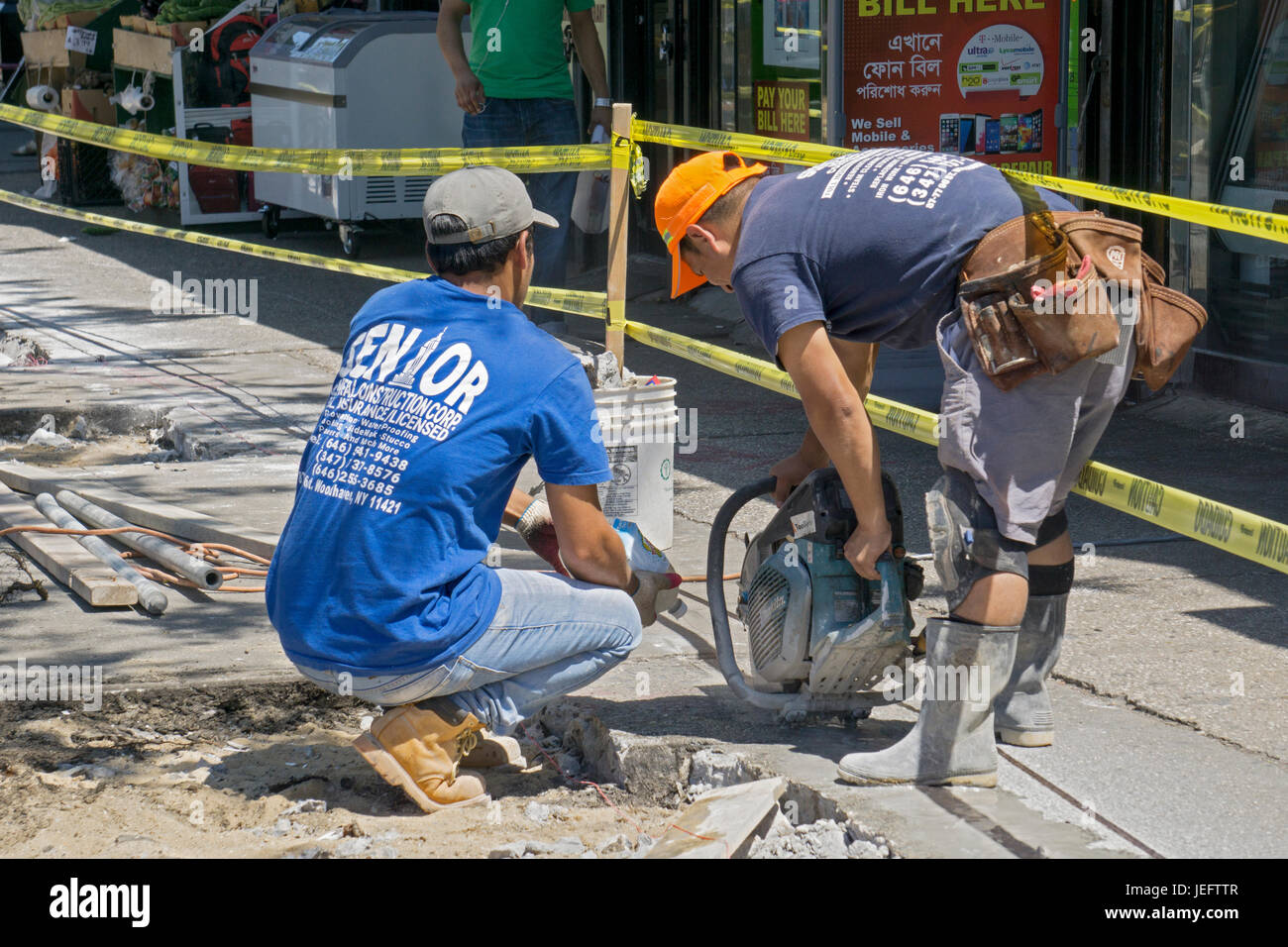 Bauarbeiter in der 37th Avenue in Jackson Heights, Queens schneiden Zement während der Sanierung eines Bürgersteig. Stockfoto