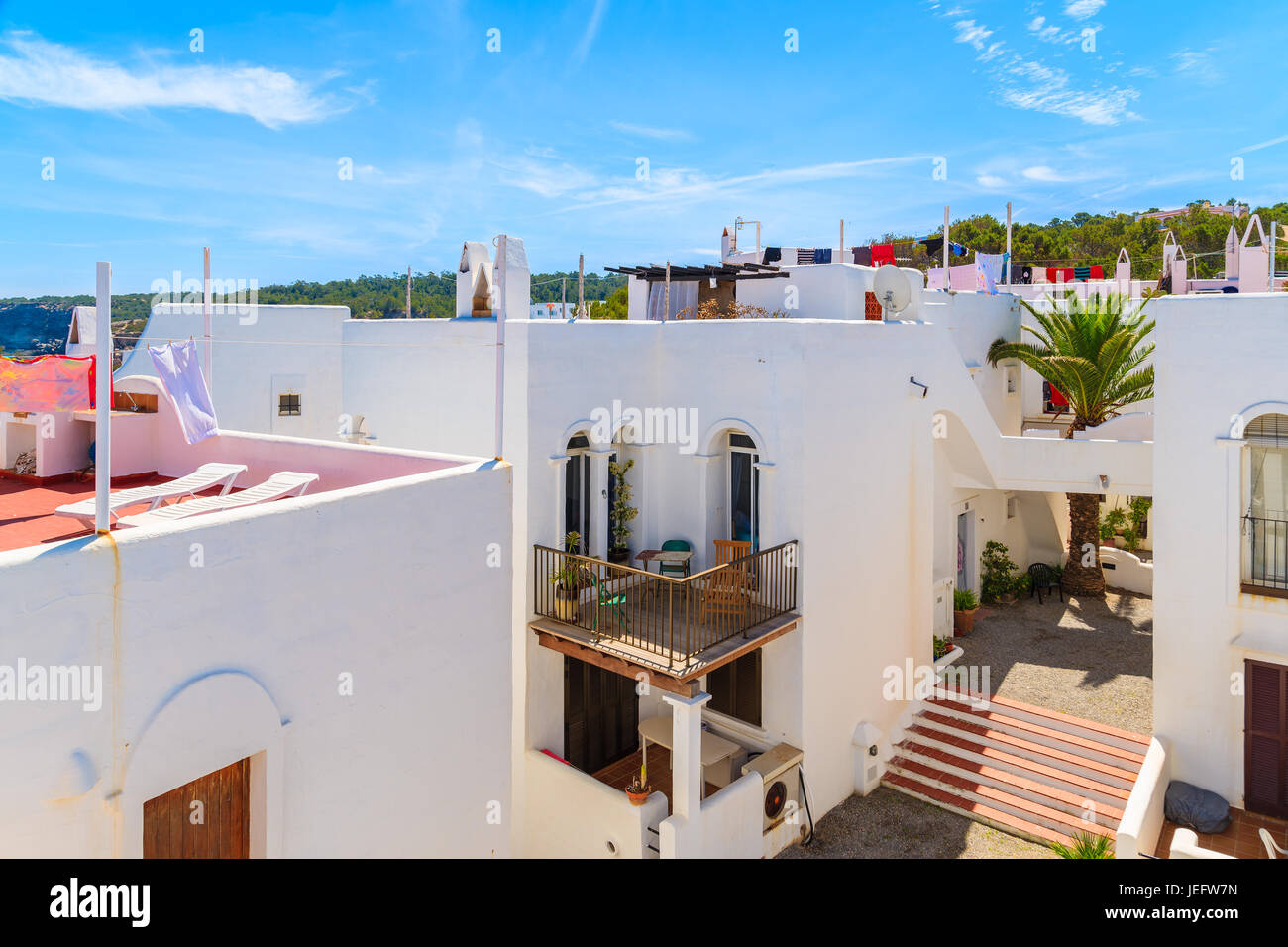 Weiße Häuser mit Wäsche trocknen auf Dächern in Cala Portinatx Bucht, Insel Ibiza, Spanien Stockfoto