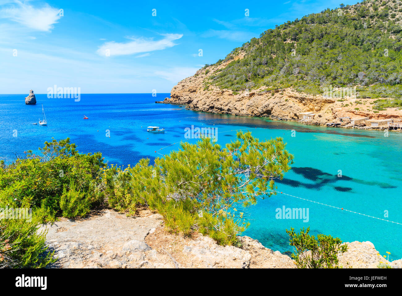 Blick auf Cala Benirras Bucht mit Fischerboot am azurblauen Meer Wasser, Insel Ibiza, Spanien Stockfoto