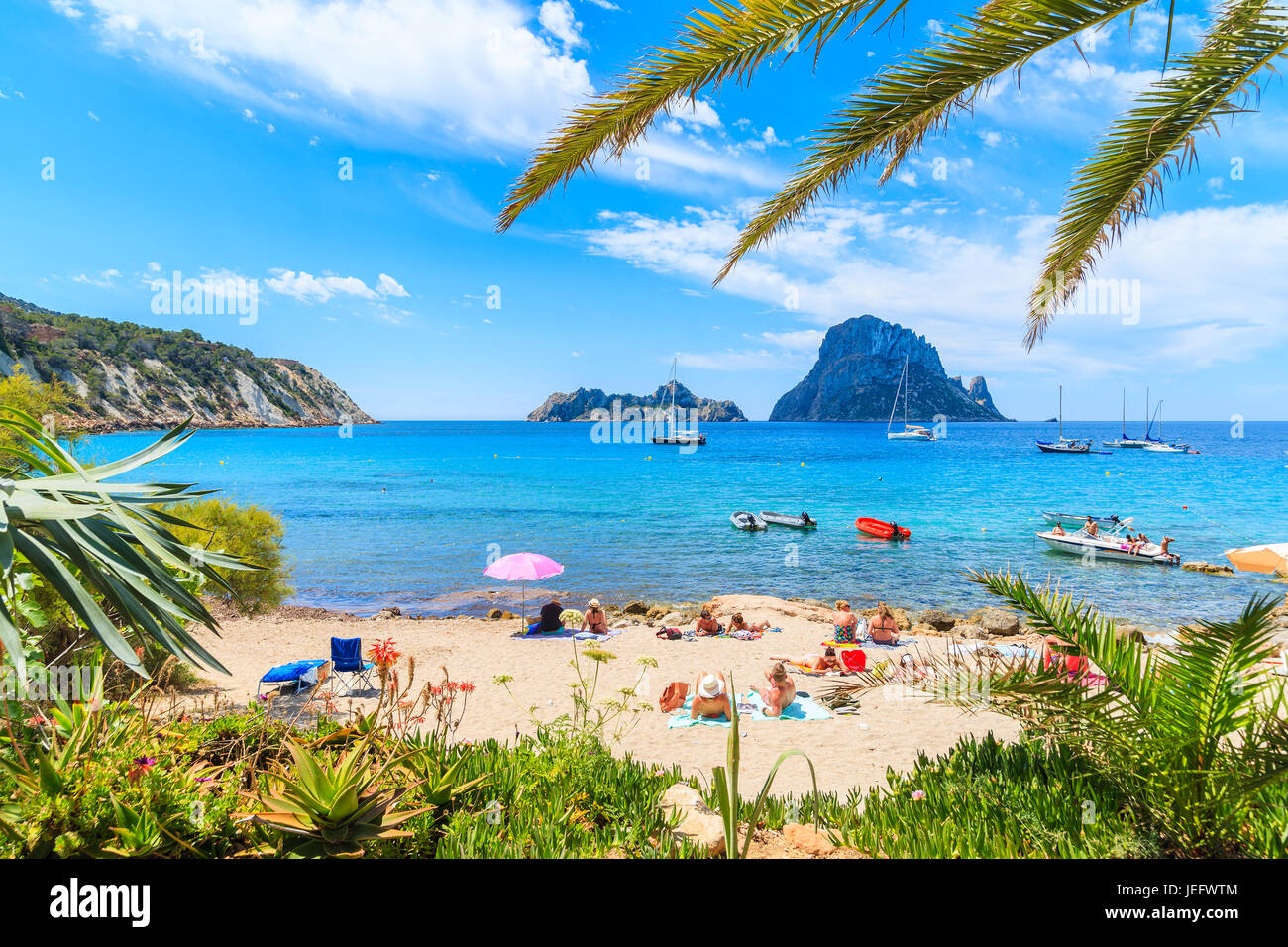 Insel IBIZA, Spanien - 18. Mai 2017: Blick auf den idyllischen Strand von Cala d ' Hort Wih Palme Blätter im Vordergrund, Insel Ibiza, Spanien. Stockfoto