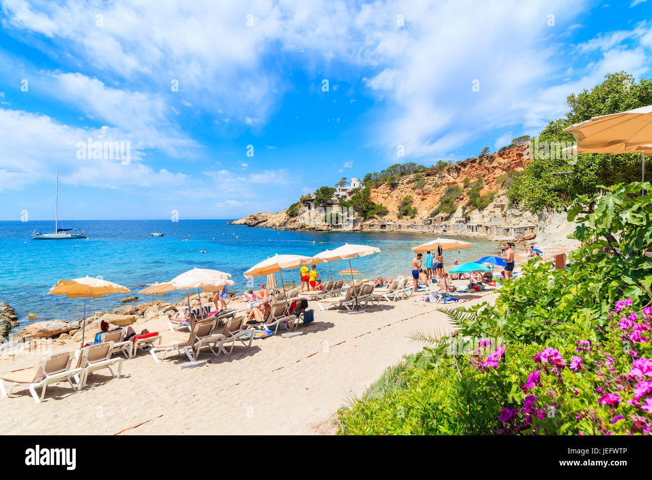 Insel IBIZA, Spanien - 18. Mai 2017: Blick auf den idyllischen Strand von Cala d ' Hort mit bunten Blumen im Vordergrund, Insel Ibiza, Spanien. Stockfoto
