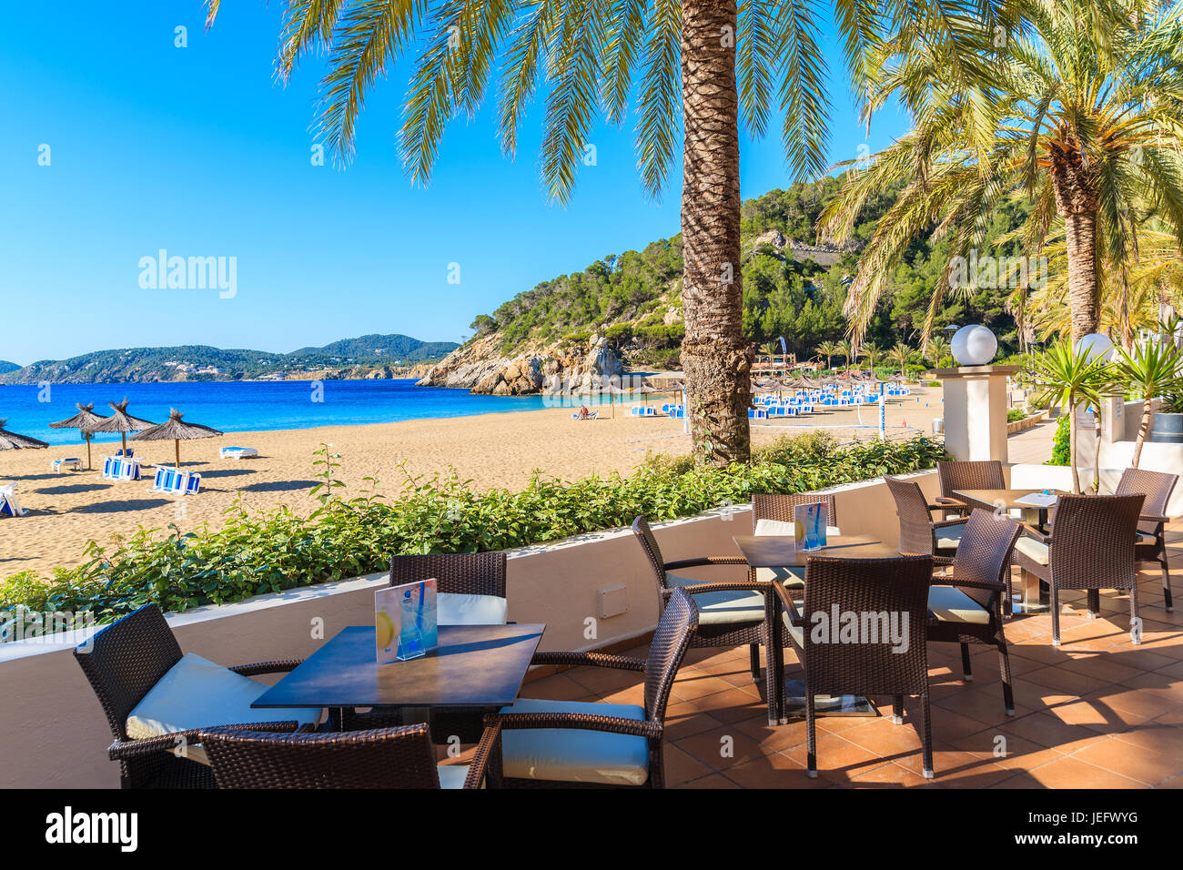 Bucht von CALA SAN VICENTE, Insel IBIZA - 19. Mai 2017: Hotel Bartische am Strand mit Palmen in Cala San Vicente Bucht, Insel Ibiza, Spanien. Stockfoto