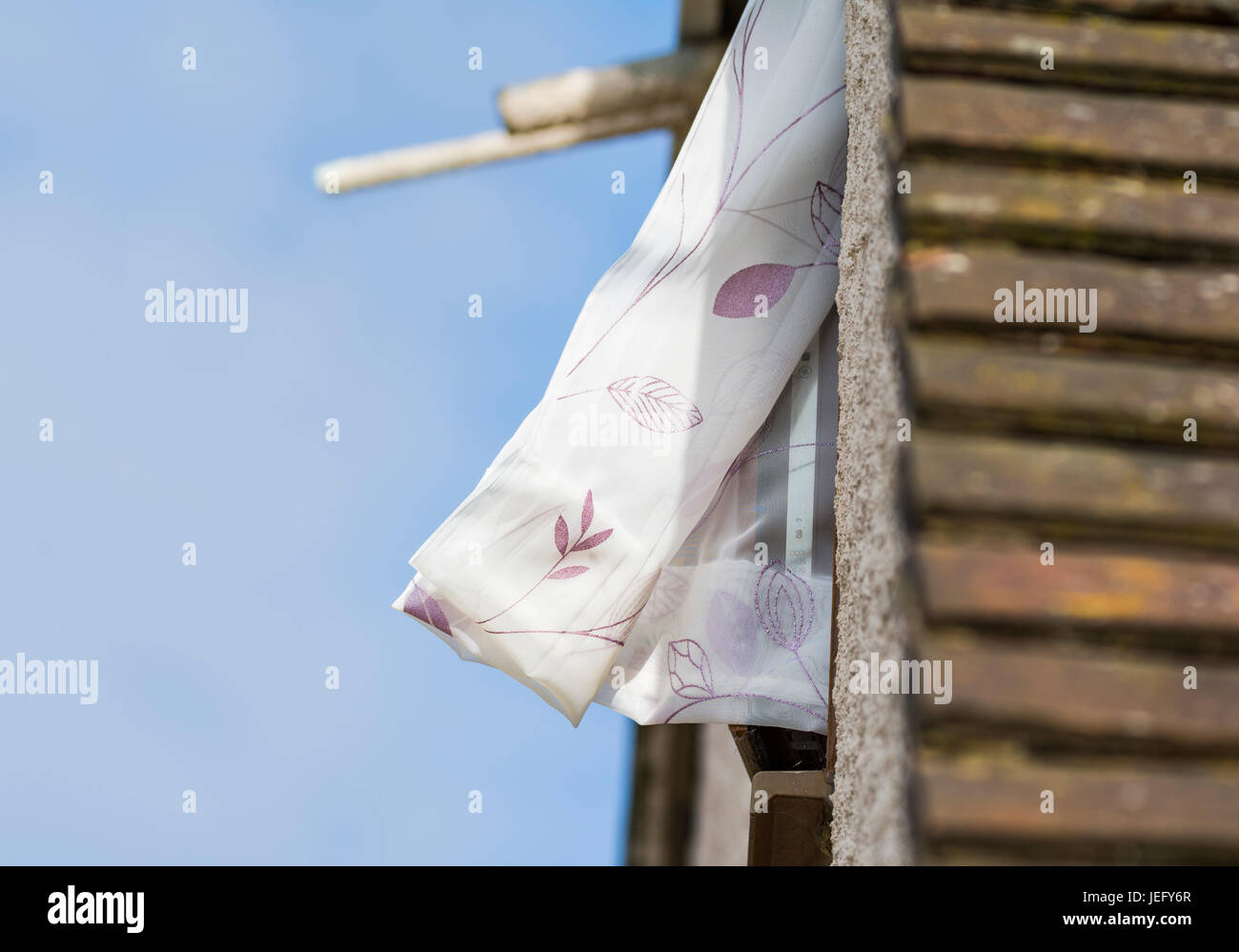 Fenster mit einem Vorhang herausragen flattern im Wind. Stockfoto