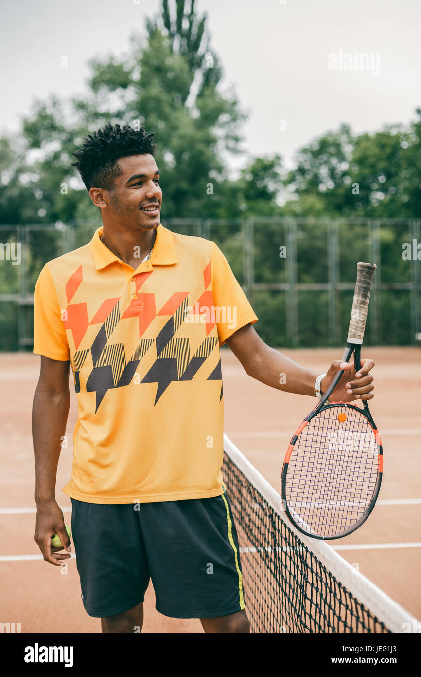 Porträt einer lächelnden Tennisspieler mit Schläger auf Tennisplatz Stockfoto