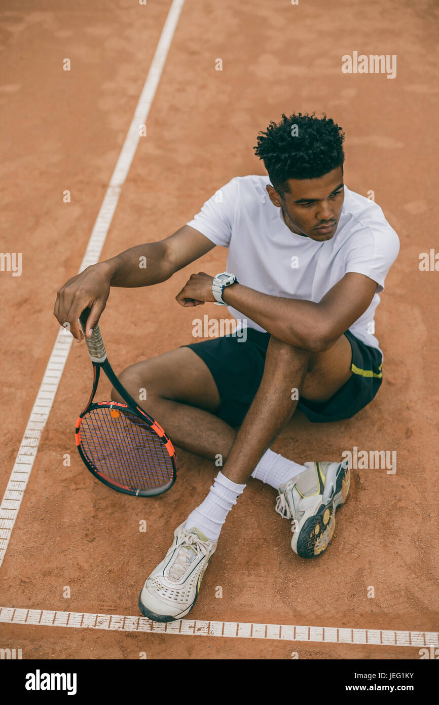 Tennisspieler Draufsicht junger Mann sitzt auf dem Boden eines Tennisplatzes Stockfoto