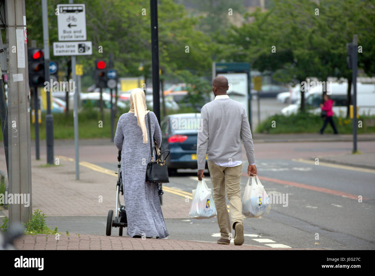 Asiatische Familie Flüchtling auf Straße in der UK alltägliche Szene Lidl Einkaufstaschen tragen Hijab Schal gekleidet Stockfoto