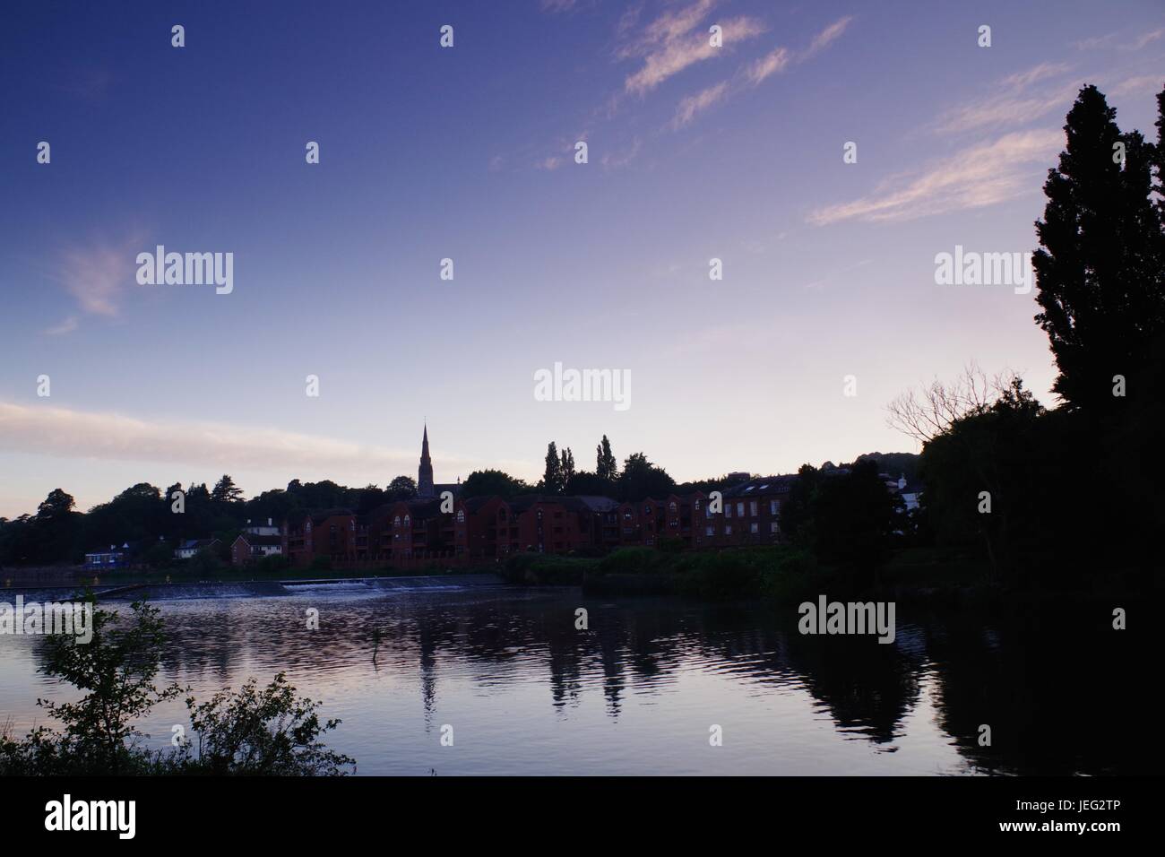 St James Weir und die Silhouette der Kirche St. Leonards bei Sonnenaufgang. Karottenhosenträger Wehr, Exeter Quay River Exe. Exeter, Devon, UK. Juni 2017. Stockfoto