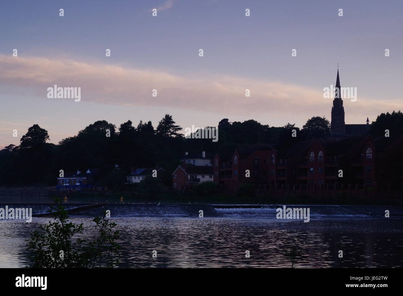 St James Weir und die Silhouette der Kirche St. Leonards bei Sonnenaufgang. Karottenhosenträger Wehr, Exeter Quay River Exe. Exeter, Devon, UK. Juni 2017. Stockfoto