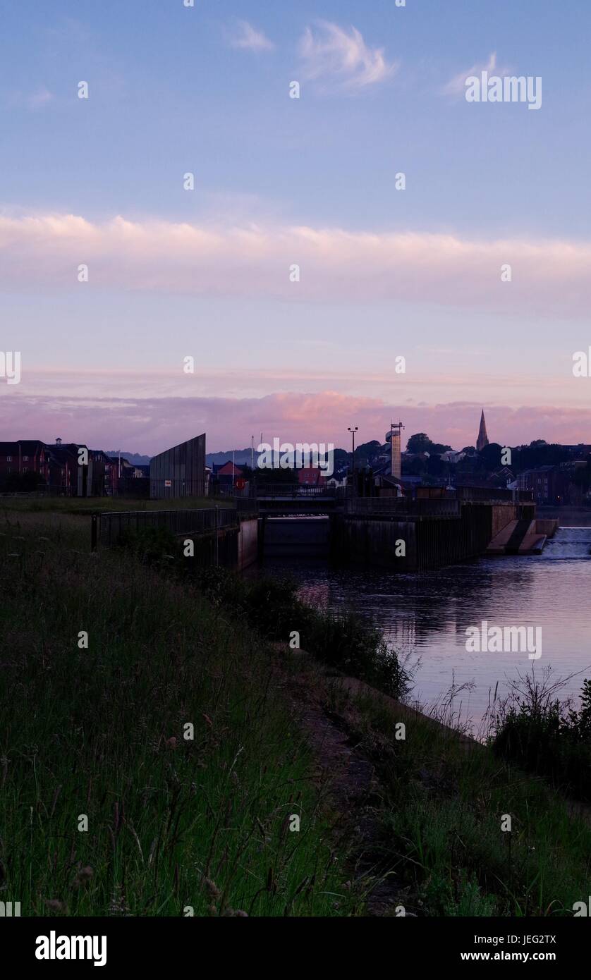 St James Weir und die Silhouette der Kirche St. Leonards bei Sonnenaufgang. Karottenhosenträger Wehr, Exeter Quay River Exe. Exeter, Devon, UK. Juni 2017. Stockfoto