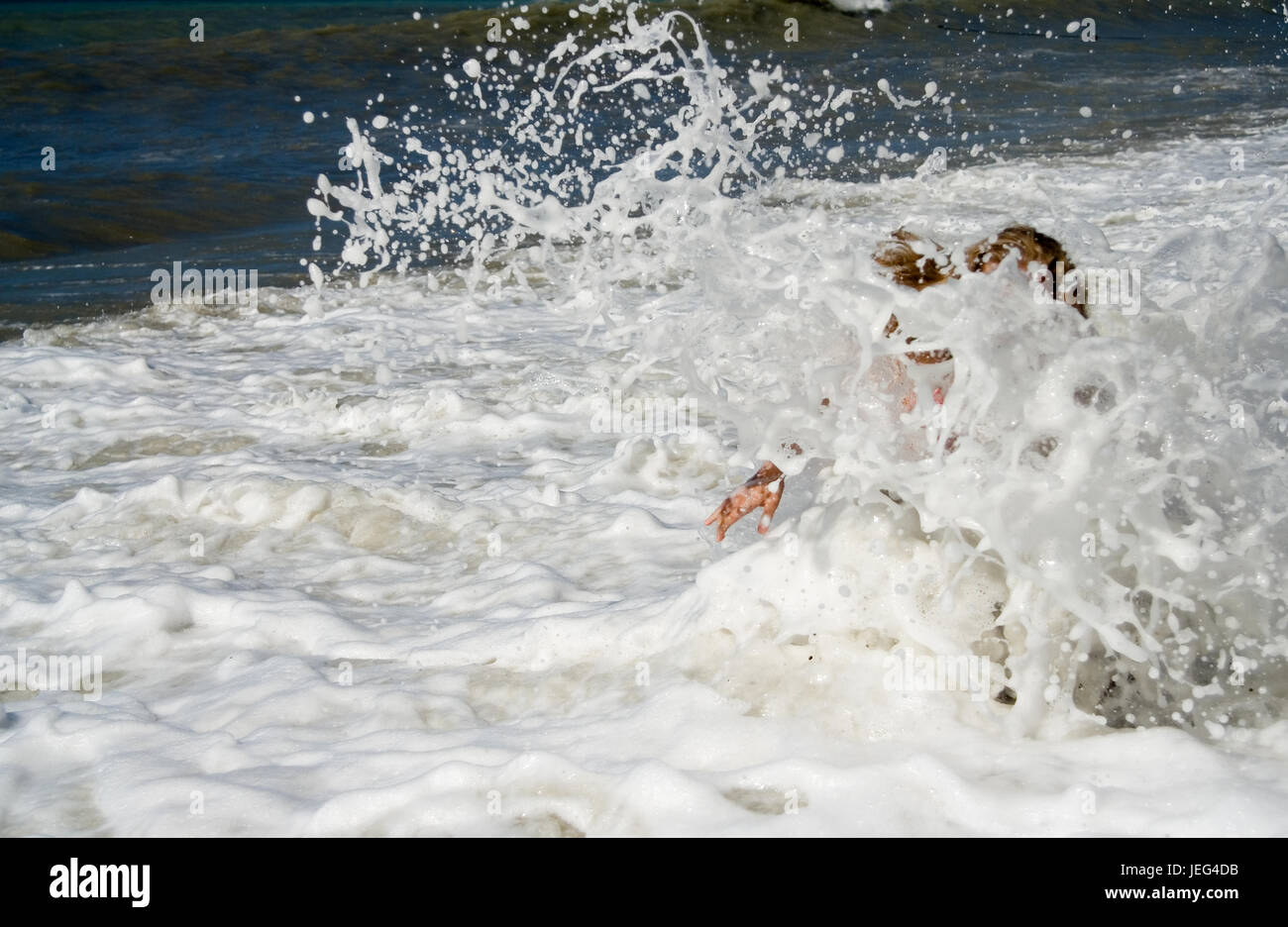 Element. Eine große Welle bedeckt das Mädchen im Meer. Stockfoto