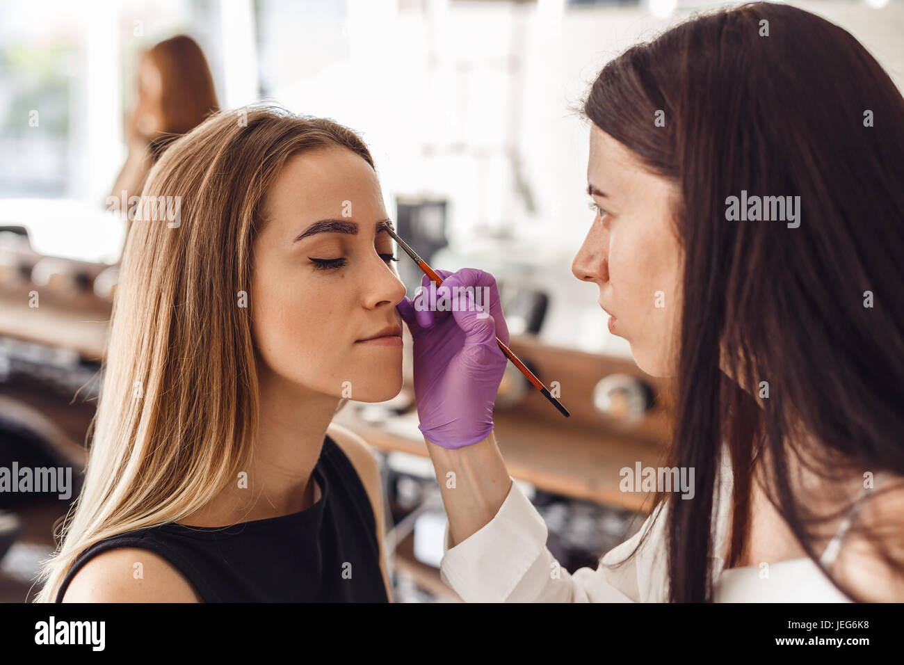 Porträt von professionellen Kosmetikerin in lila Handschuhe machen permanente Augenbrauen Stockfoto