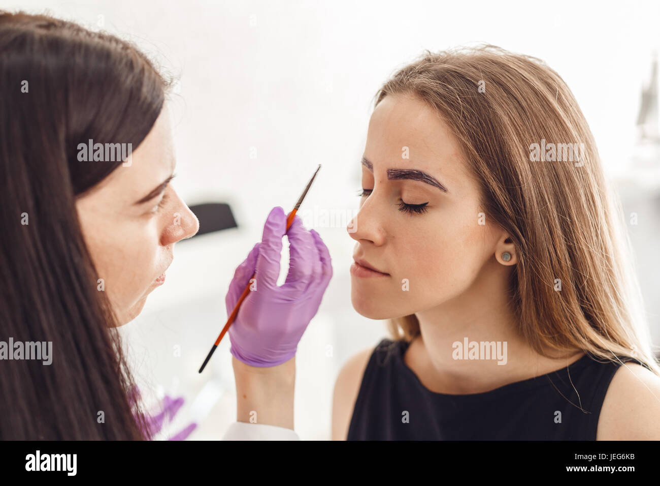 Porträt von professionellen Kosmetikerin in lila Handschuhe machen permanente Augenbrauen Stockfoto