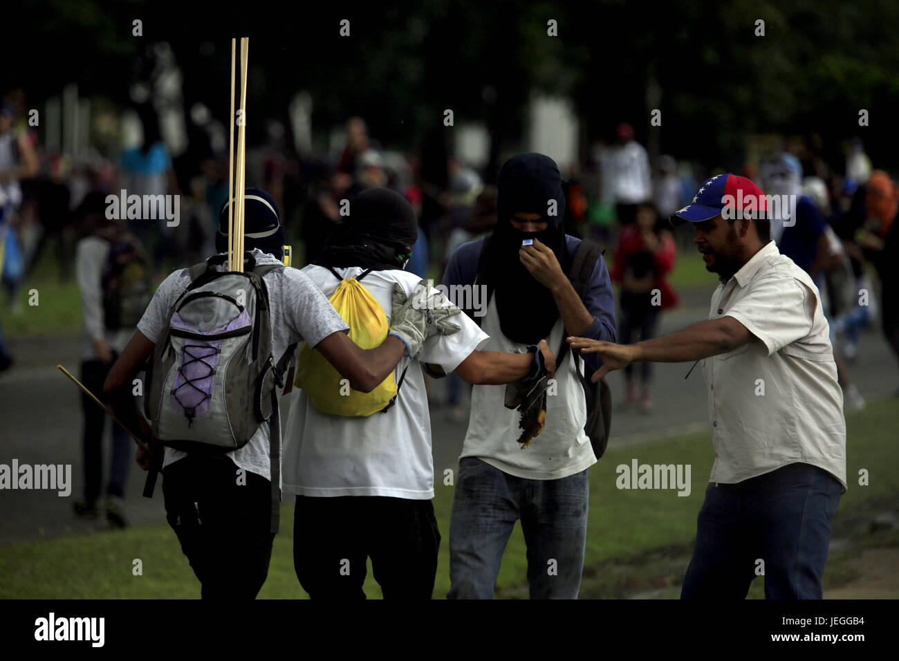 Naguanagua, Carabobo, Venezuela. 24. Juni 2017. Ein Kapuzen junger Mann, der eine Konfrontation mit der Bolivarischen Nationalpolizei teilnimmt, wird von seinen Kameraden unterstützt, nachdem ein Feuerwerkskörper explodiert in der Hand, am Ende der Nachricht Marsch auf die ff aa Nn, die ein Besuch in Fort Paramacay, In Naguanagua, Bundesstaat Carabobo war. : Bildnachweis Juan Carlos Hernandez: Juan Carlos Hernandez/ZUMA Draht/Alamy Live-Nachrichten Stockfoto