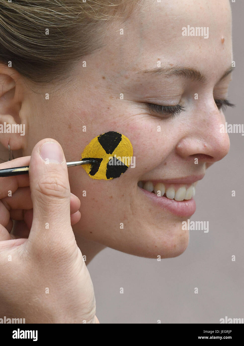 Aachen, Deutschland. 25. Juni 2017. Ein Teilnehmer an den Protesten hat ihre Wange gemalt mit einem Symbol Strahlung während des Protestes "Chain Reaction" gegen einen belgischen Kernreaktor an der Grenze zu den Niederlanden in Aachen, Deutschland, 25. Juni 2017. Die Demonstranten fordern eine sofortige Stilllegung von Kraftwerkseinheiten Tihange 2 und3 Doel, die Sicherheit durch Tausende von mikroskopisch kleinen Rissen bestritten wird. Foto: Henning Kaiser/Dpa/Alamy Live News Stockfoto