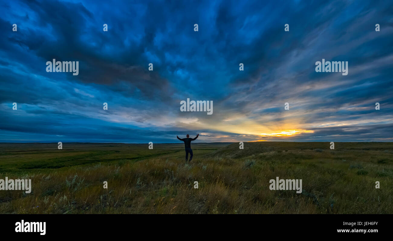 Mann, stehend mit seinen Armen verteilt offen bei Tagesanbruch im Grasslands National Park; Saskatchewan, Kanada Stockfoto