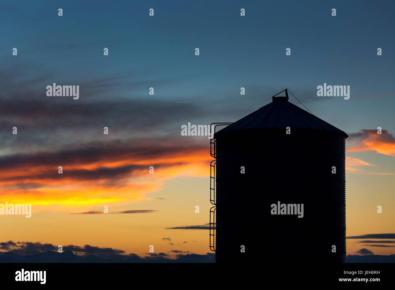 Silhouette der großen Metall-Silo mit bunten Wolken bei Sonnenuntergang mit blauem Himmel; Alberta, Kanada Stockfoto