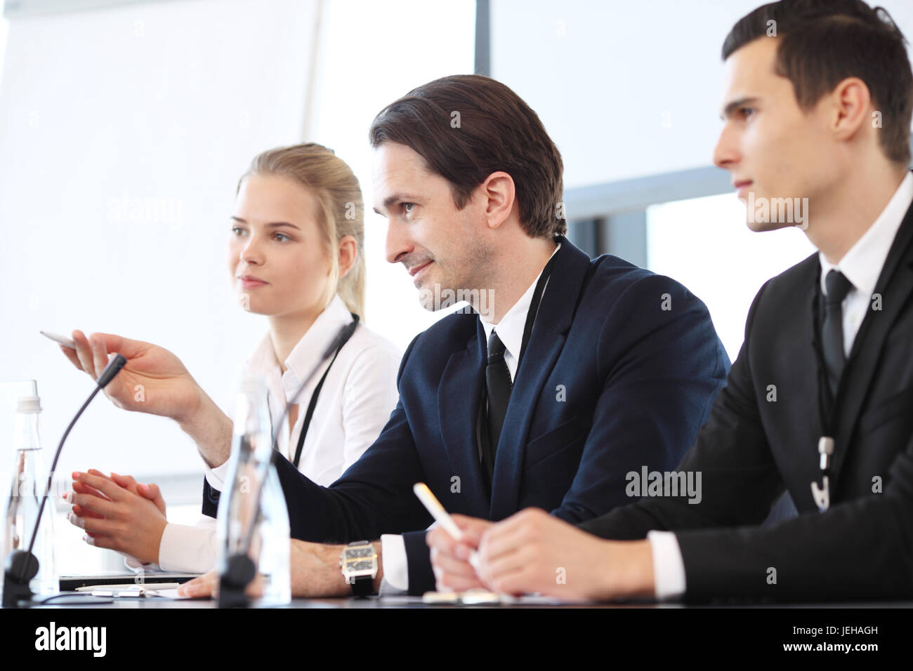 Sprechergruppe auf Business Meeting am Tisch mit Mikrofonen Stockfoto