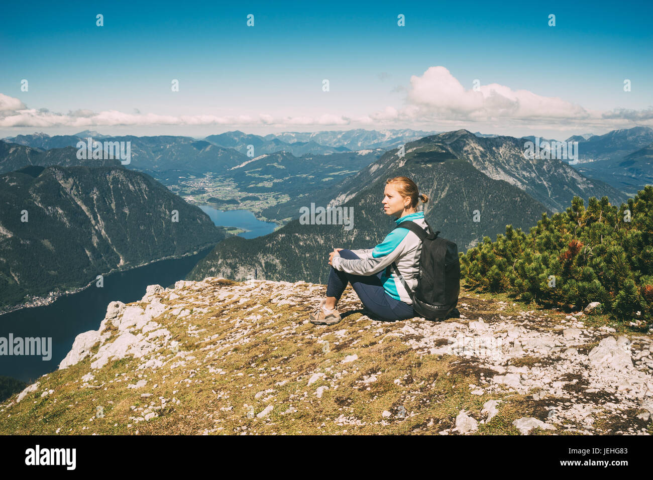 Junge schöne Frau am Rande des Berges gegen Tal mit See Stockfoto