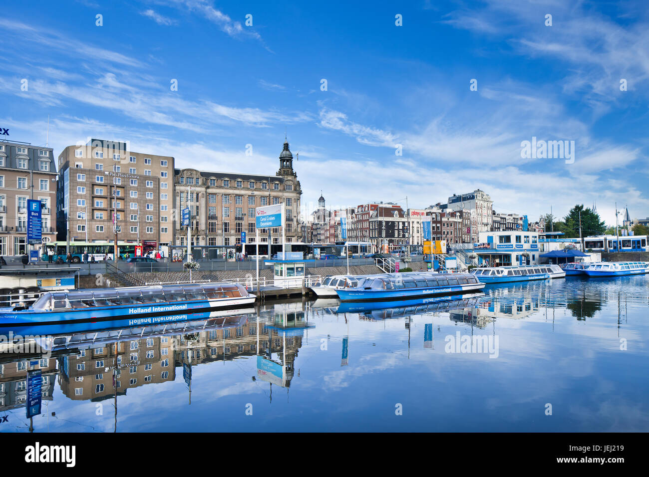 AMSTERDAM-AUG. 27, 2014. Vertäute Tourboote, die sich in einem blauen Kanal spiegeln. Zahlreiche Unternehmen bieten Grachtenfahrten durch Amsterdam an, darunter Holland International. Stockfoto