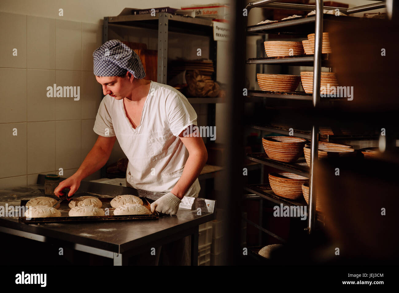 ein Bäcker macht manuelle Einschnitte auf den Teig für das Brot. Die Herstellung von Bread.Bakery Stockfoto