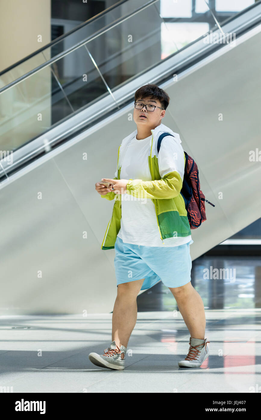 PEKING-18. MAI 2016. Übergewichtiger junger Mann in einem Einkaufszentrum. Die durchschnittliche Taille der chinesischen städtischen Männchen hat von 63.5 cm in 1985 auf 76.2 cm gegangen. Stockfoto