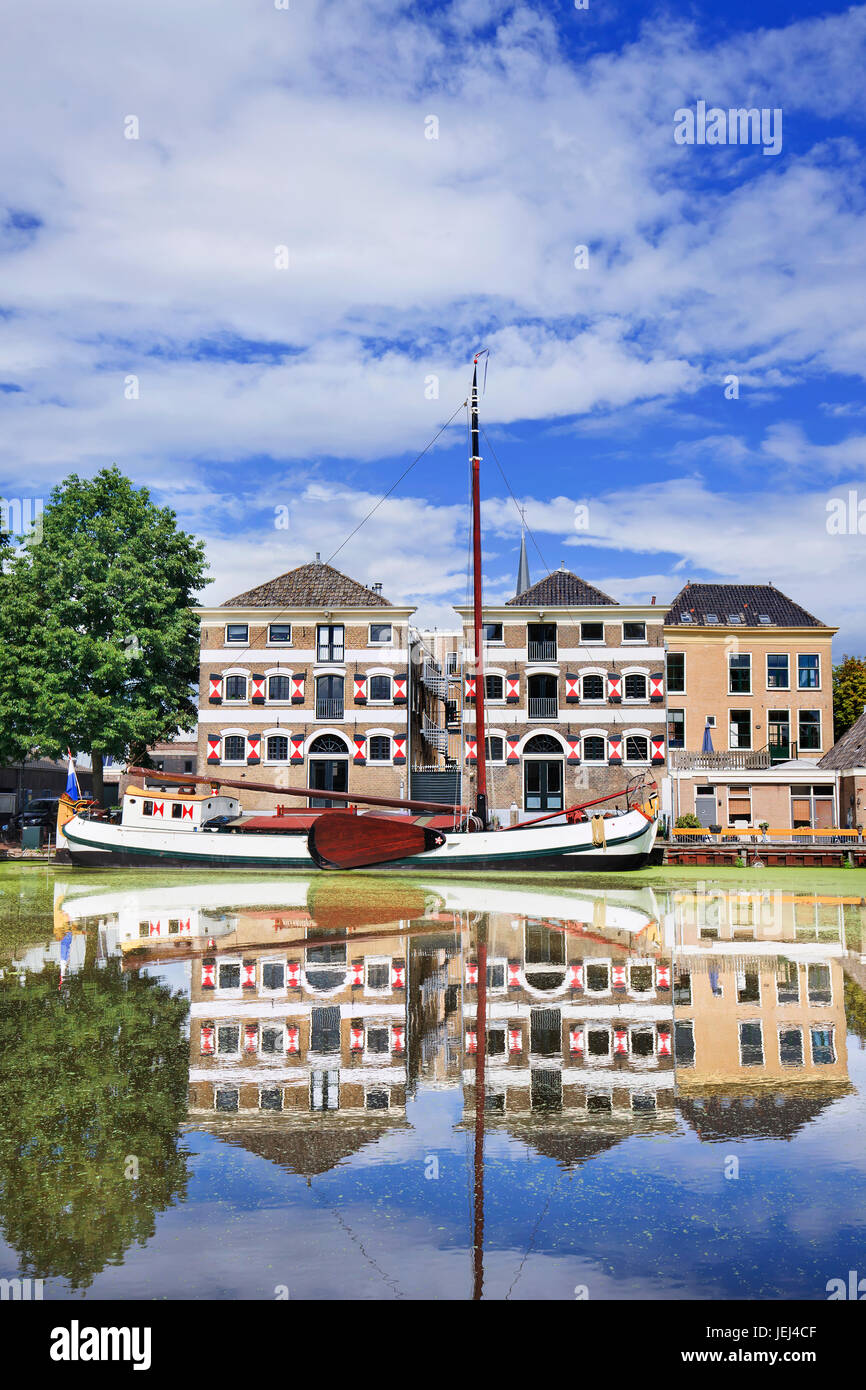 Renoviertes monumentales Herrenhaus mit einem weißen festgemachten Boot spiegelt sich in einem Kanal. Stockfoto