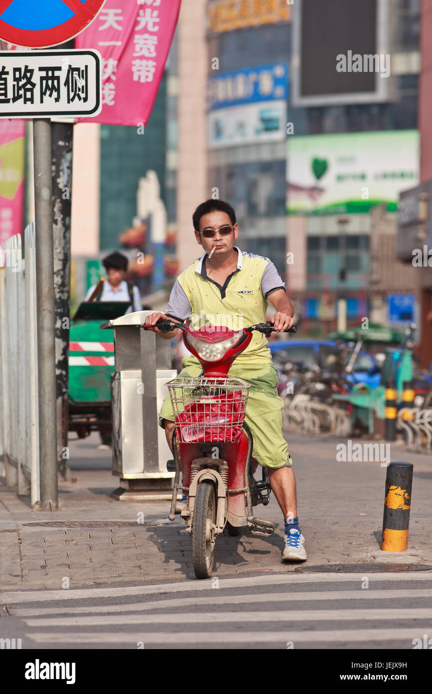 BEIJING-JULI 24, 2015. Mann auf e-Bike raucht Zigarette. China hat mehr als 300 Millionen Raucher. Fast 30 % der Erwachsenen Rauchen, davon 53 % aller Männer. Stockfoto