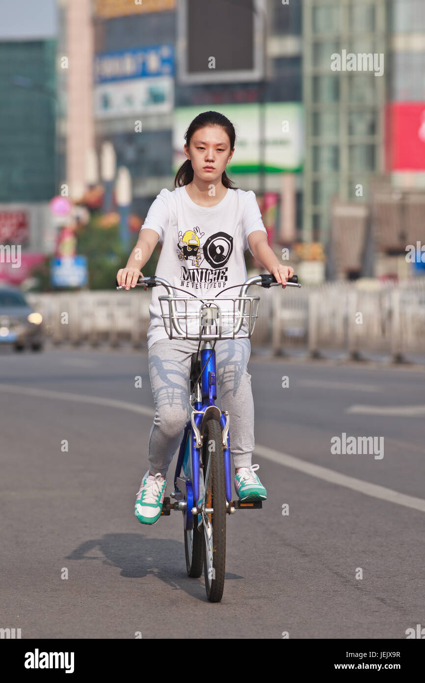 PEKING - 24. JULI 2015. Junge Mädchen auf dem öffentlichen Fahrrad. Fahrradnutzung ermöglicht die kurzfristige Anmietung, es ist ein sehr beliebter Transportmodus. Stockfoto