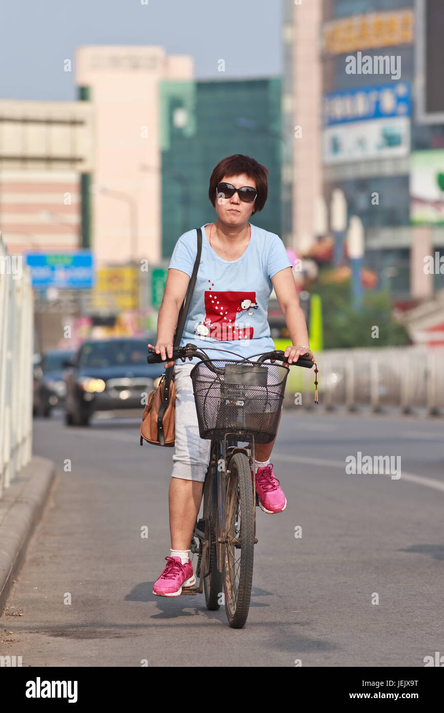 PEKING - 24. JULI 2015. Modische Frau auf dem Fahrrad. Obwohl die schnelle Vervielfachung von Autos in China das Fahrrad nach wie vor am häufigsten benutzt wird. Stockfoto