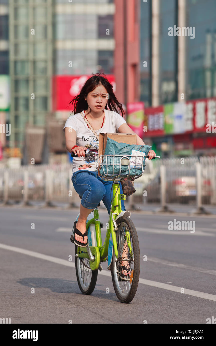 PEKING - 24. JULI 2015. Junge Mädchen auf dem öffentlichen Fahrrad. Fahrradnutzung ermöglicht die kurzfristige Anmietung, es ist ein beliebter Transportmodus. Stockfoto