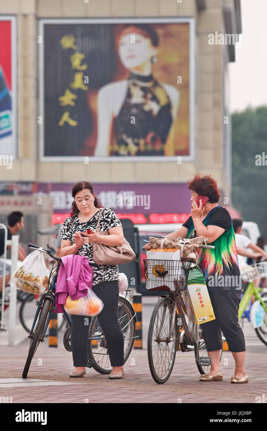 PEKING - 27. JULI 2015. Zwei Frauen mittleren Alters, die mit ihren Smartphones beschäftigt sind. China hat derzeit 519,7 Millionen Smartphone-Nutzer. Stockfoto