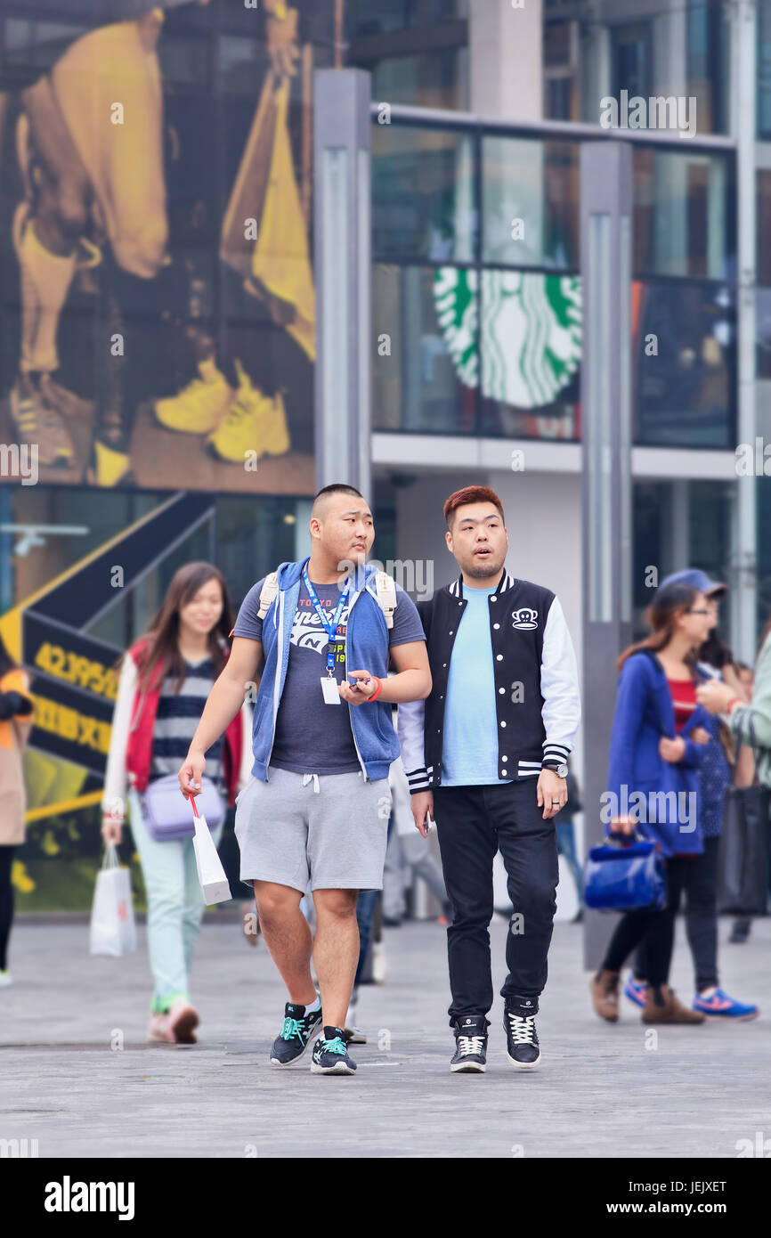PEKING - 19. OKTOBER 2014. Junge Männer in Sportswear im Einkaufsviertel. Die Chinesen übertrafen die Amerikaner als die größten Konsumenten von Luxusgütern. Stockfoto