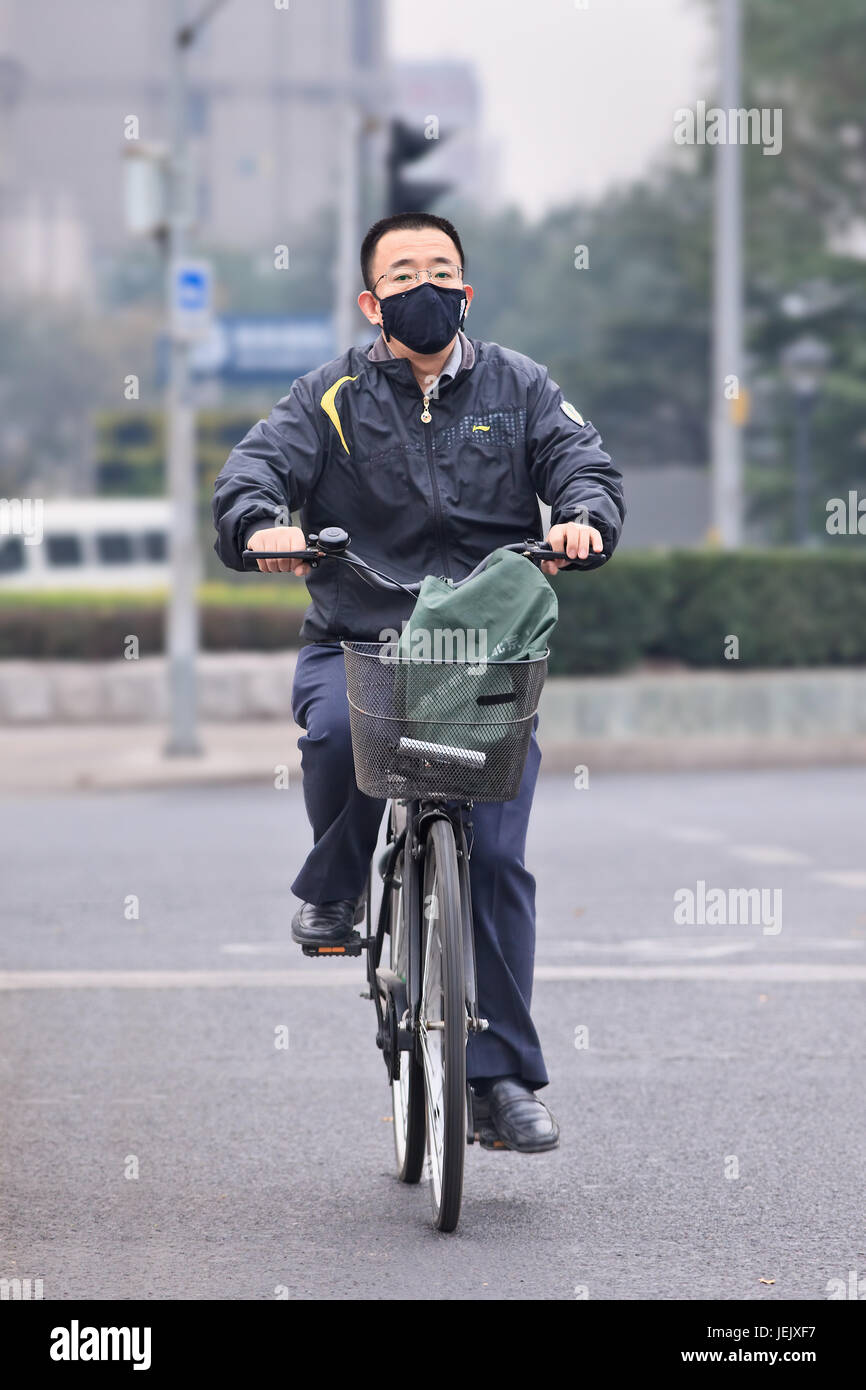 PEKING - 19. OKTOBER 2014. Radfahrer mit Gesichtsmaske gegen Smog. Peking erhöhte seinen Smog auf Orange, weil die schlechte Luftqualität. Stockfoto