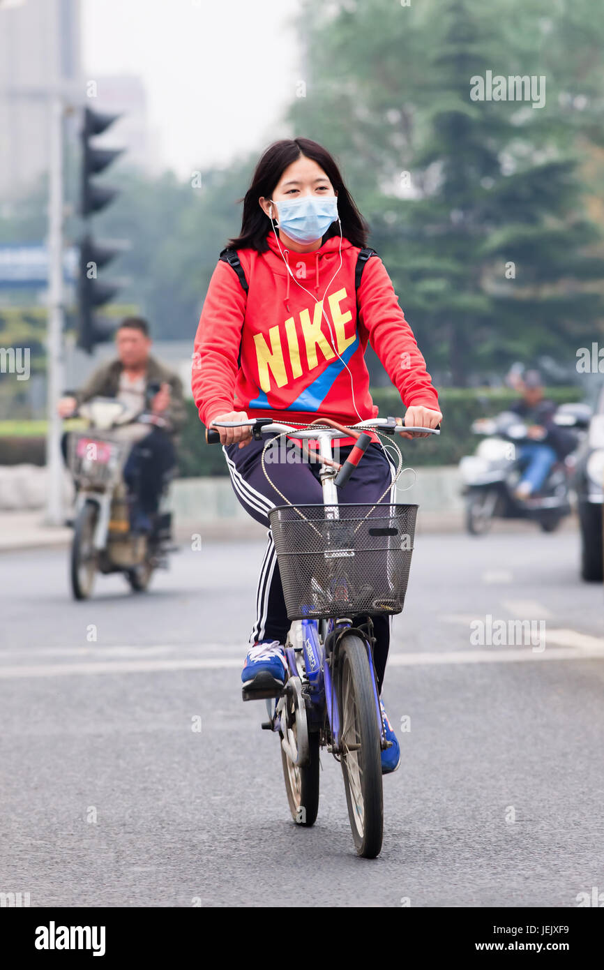 PEKING-OCT. 19, 2014. Maskierter Radfahrer in rauchiger Stadt. Peking erhöhte Smog auf Orange, weil die schlechte Luftqualität. Stockfoto