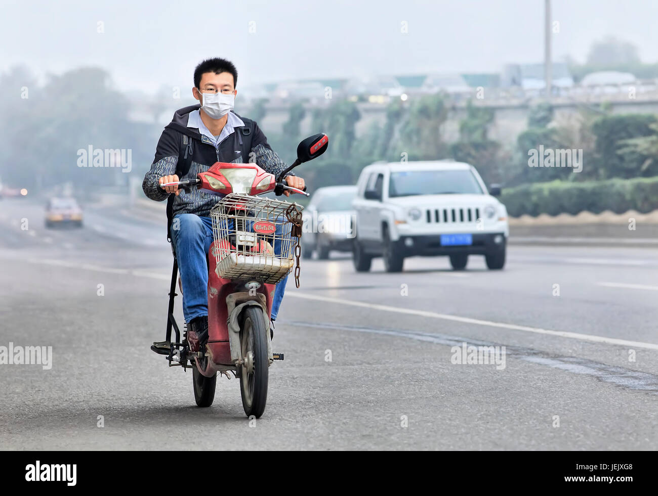 PEKING - OKT. 6. Der junge Mann auf einem E-Bike bedeckt seinen Mund gegen Smog. Die Überwachung der US-Botschaft zeigte, dass die Luft in Peking sehr ungesund war. Stockfoto