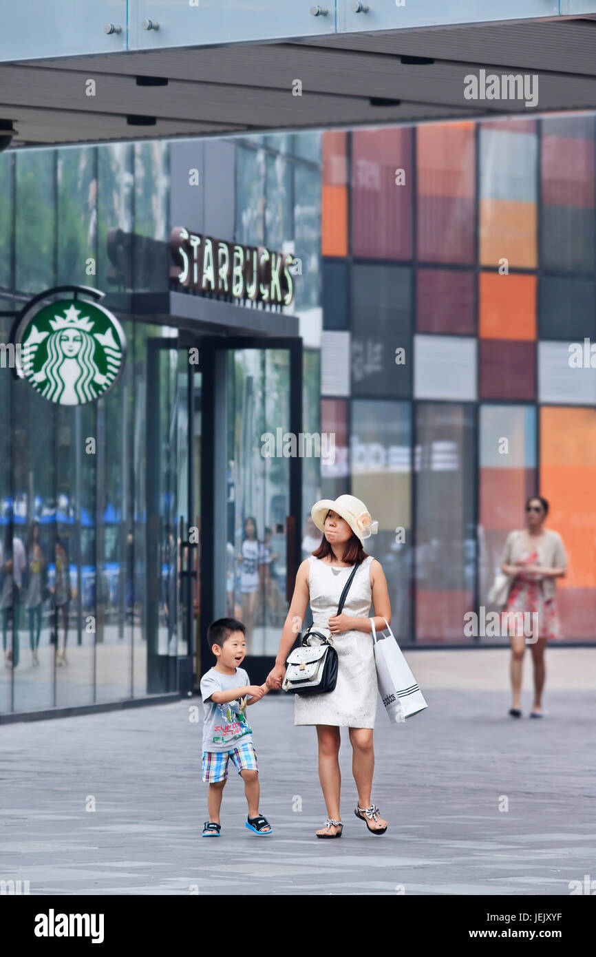 PEKING - 25. JUNI 2014. Junge Frau mit Kind im Einkaufsviertel. Nach der neuen Politik dürfen chinesische Paare zwei Kinder haben. Stockfoto