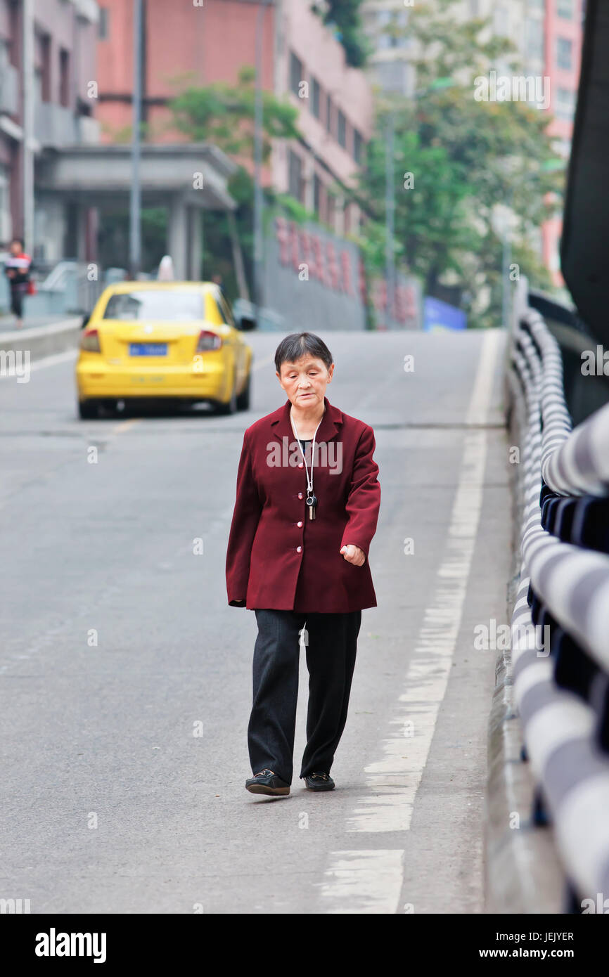 CHONGQING - 4. NOVEMBER 2014. Alte Frau läuft auf der Straße. Der Regierungsbericht prognostiziert, dass China im Jahr 2030 die am meisten gealterte Gesellschaft der Welt wird. Stockfoto