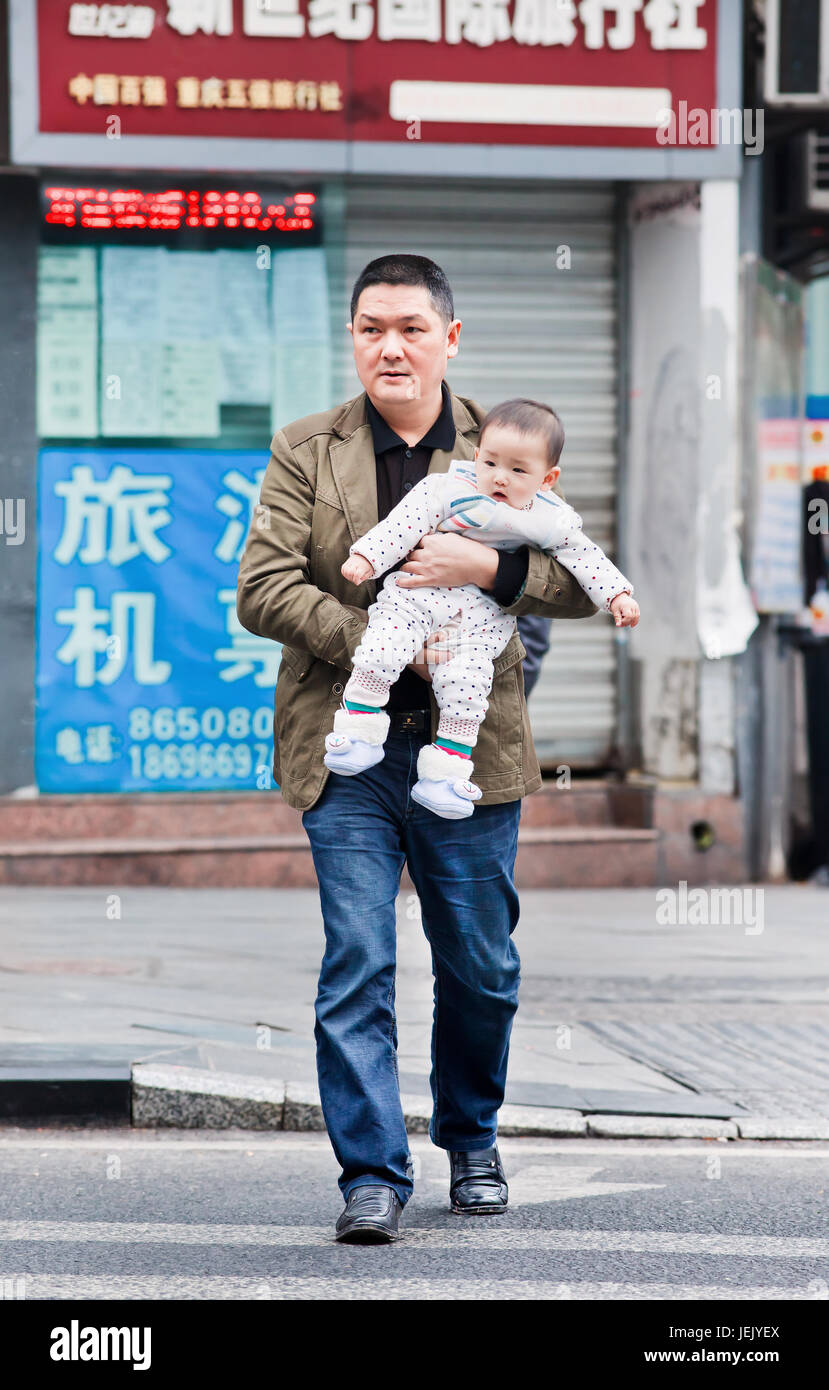 CHONGQING-NOV. 4, 2014. Vater trägt jungen Sohn. Nach 30 Jahren der Ein-Kind-Politik Chinas werden viele Familien das zulassen eines zweiten Kindes nicht nutzen. Stockfoto
