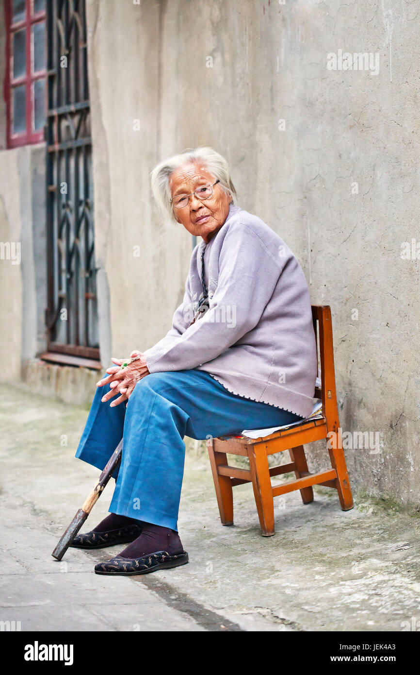 YANGZHOU - CHINA - SEPT. 25., 2010. Alte chinesische Frau draußen sitzen auf einem Stuhl. Die ältere Bevölkerung (60 Jahre und älter) in China 128 Millionen. Stockfoto