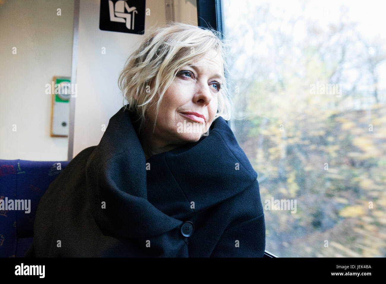 Reife Frau Blick durch Fenster in Zug Stockfoto