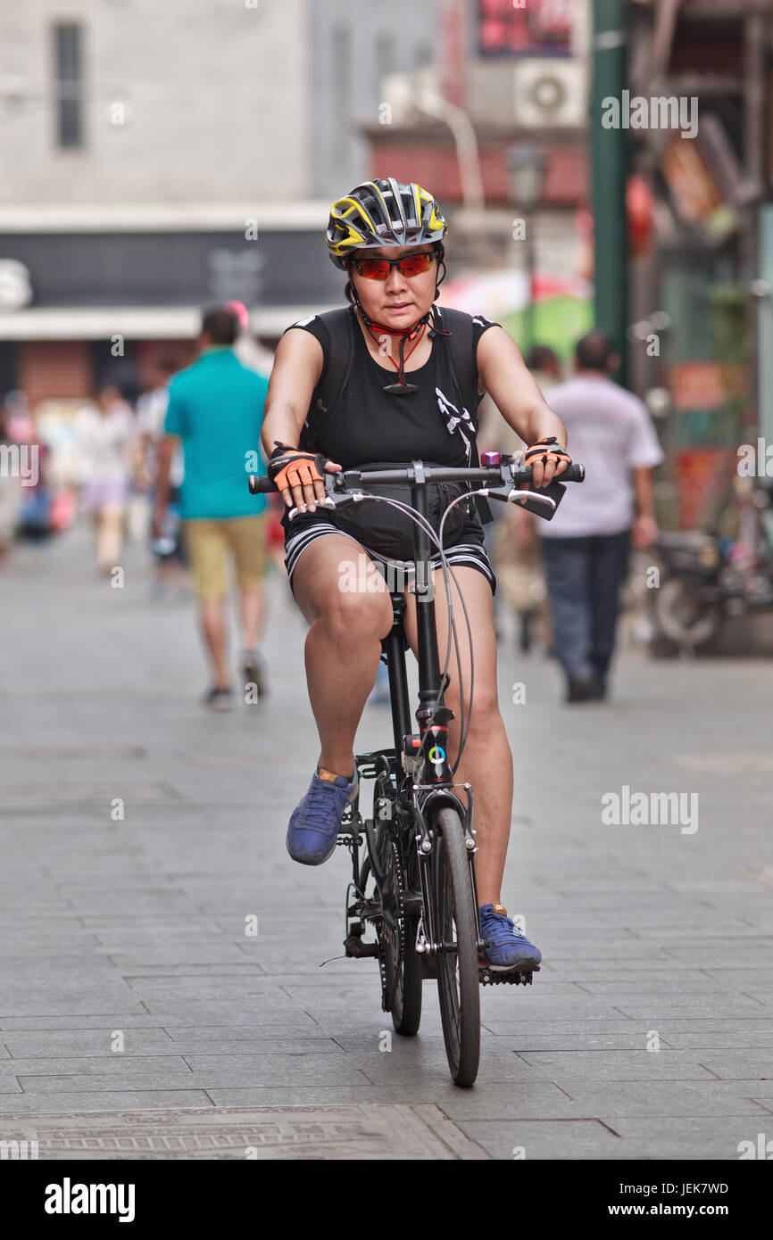 PEKING, 9. JUNI 2015. Sportliche Frau mittleren Alters. Vor drei Jahrzehnten war das Fahrrad der Menschen der wichtigste Verkehrsträger in Peking. Stockfoto