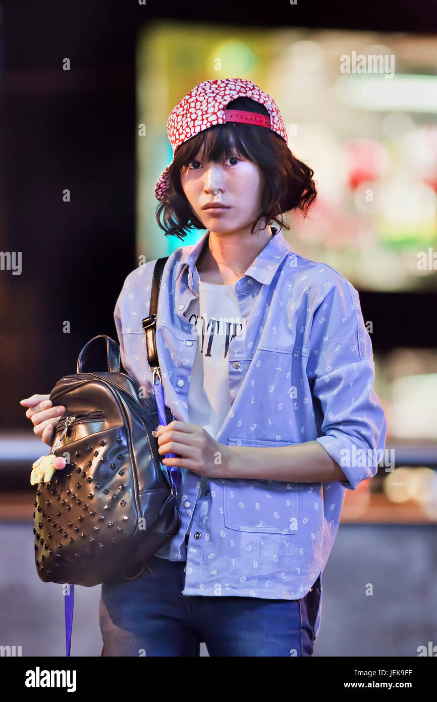 KUNMING - 10. JULI 2014. Modisches junges Mädchen mit einer modischen Tasche in einem Einkaufsviertel in der Innenstadt. Stockfoto