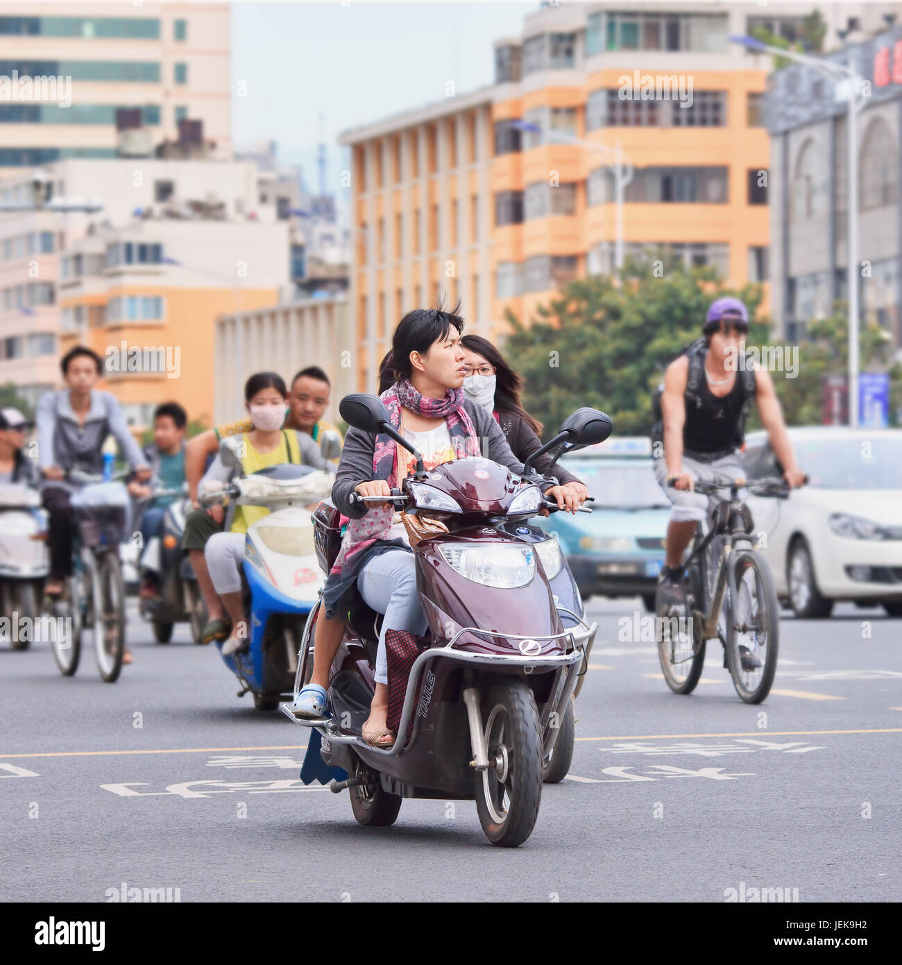 KUNMING - 30. JUNI 2014. Junge Frau auf dem Elektrobike. Viele Elektrofahrräder in China sind das E-Bike im Roller-Stil, das Pedale haben kann oder nicht. Stockfoto