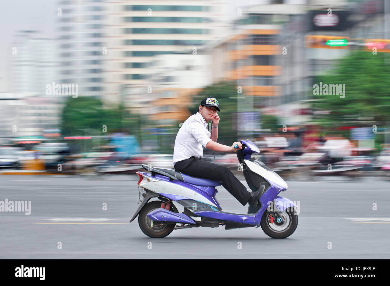 KUNMING - 5. JULI 2014. Mann auf einem elektrischen Fahrrad. Schätzungsweise 200 Millionen Chinesen verwenden jetzt E-Bikes, 1.000-mal mehr als vor 15 Jahren. Stockfoto