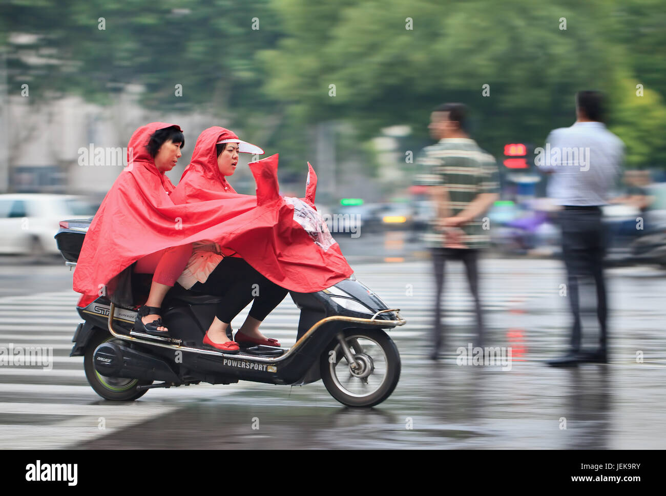 NANJING - 24. MAI 2014. Frauen auf E-Bike mit Regenschutz. Nanjing hat ein feuchtes subtropisches Klima mit viel Niederschlag. Die Sommer sind heiß, die Winter kalt. Stockfoto