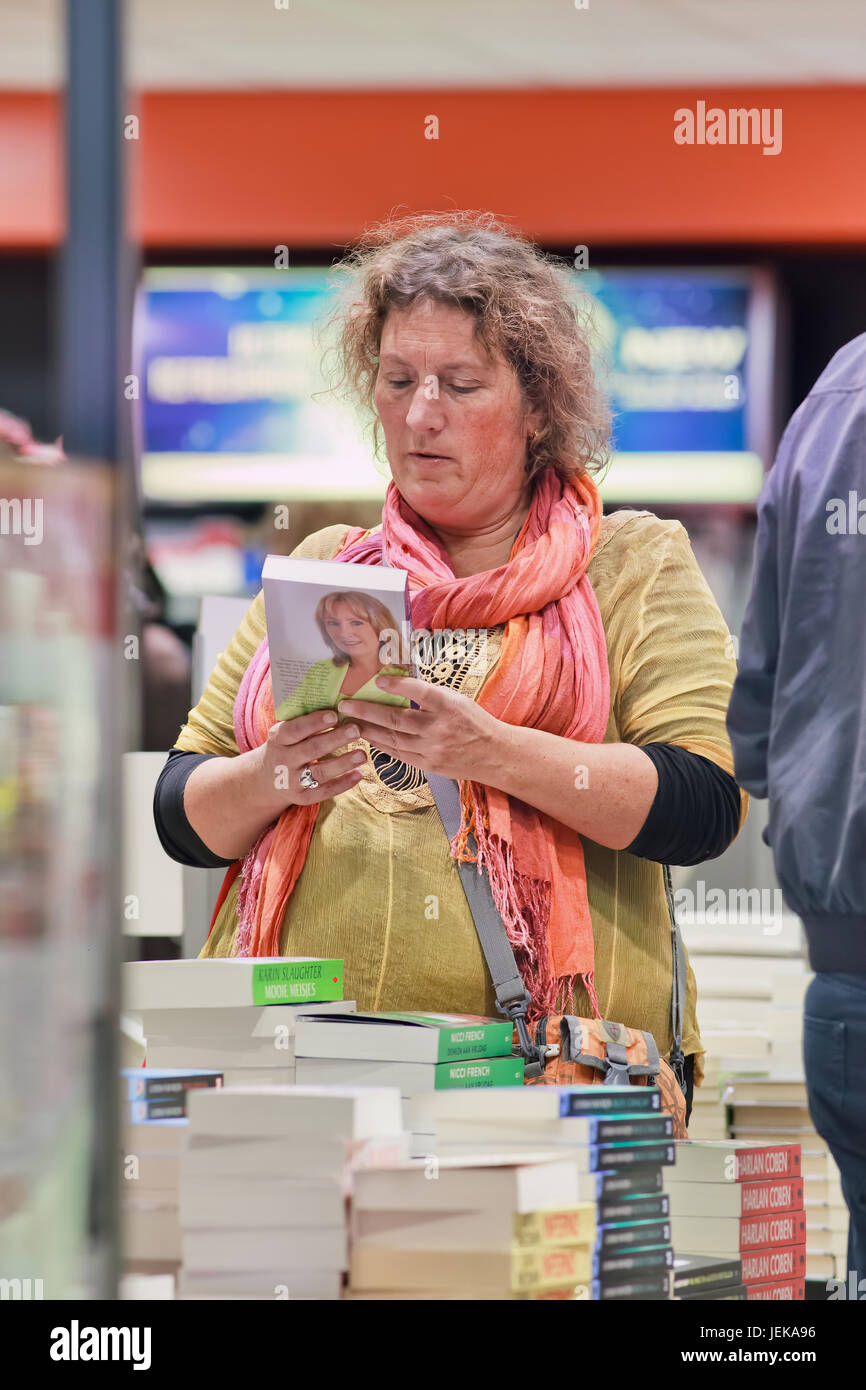 AMSTERDAM-OCT.23, 2015. Frau im Duty Free Buchladen am Flughafen Schiphol. Reisende können im Einkaufsviertel kostenlos einkaufen. Stockfoto