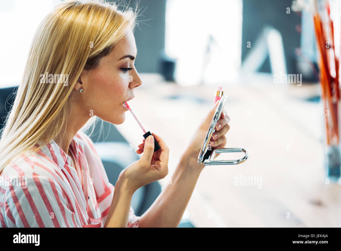 Junge schöne Frau, die Anwendung von Make-up mit kleinen Spiegel im Beauty-salon Stockfoto