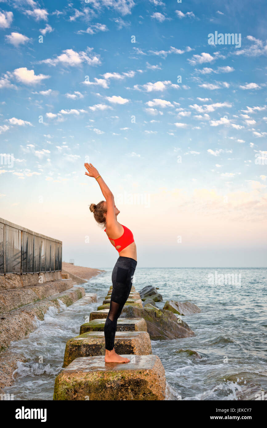 Frau, Yoga zu praktizieren, indem Sie das Meer stehen auf Felsen Stockfoto