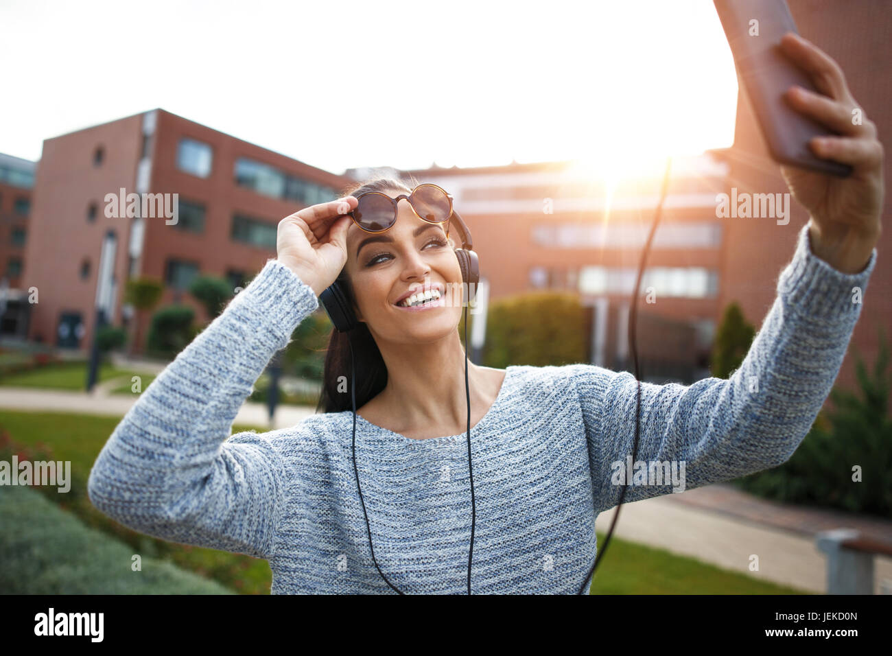 Junge Frau, die Tablette in der Stadt, im Freien bei Sonnenuntergang Selfie indem Stockfoto