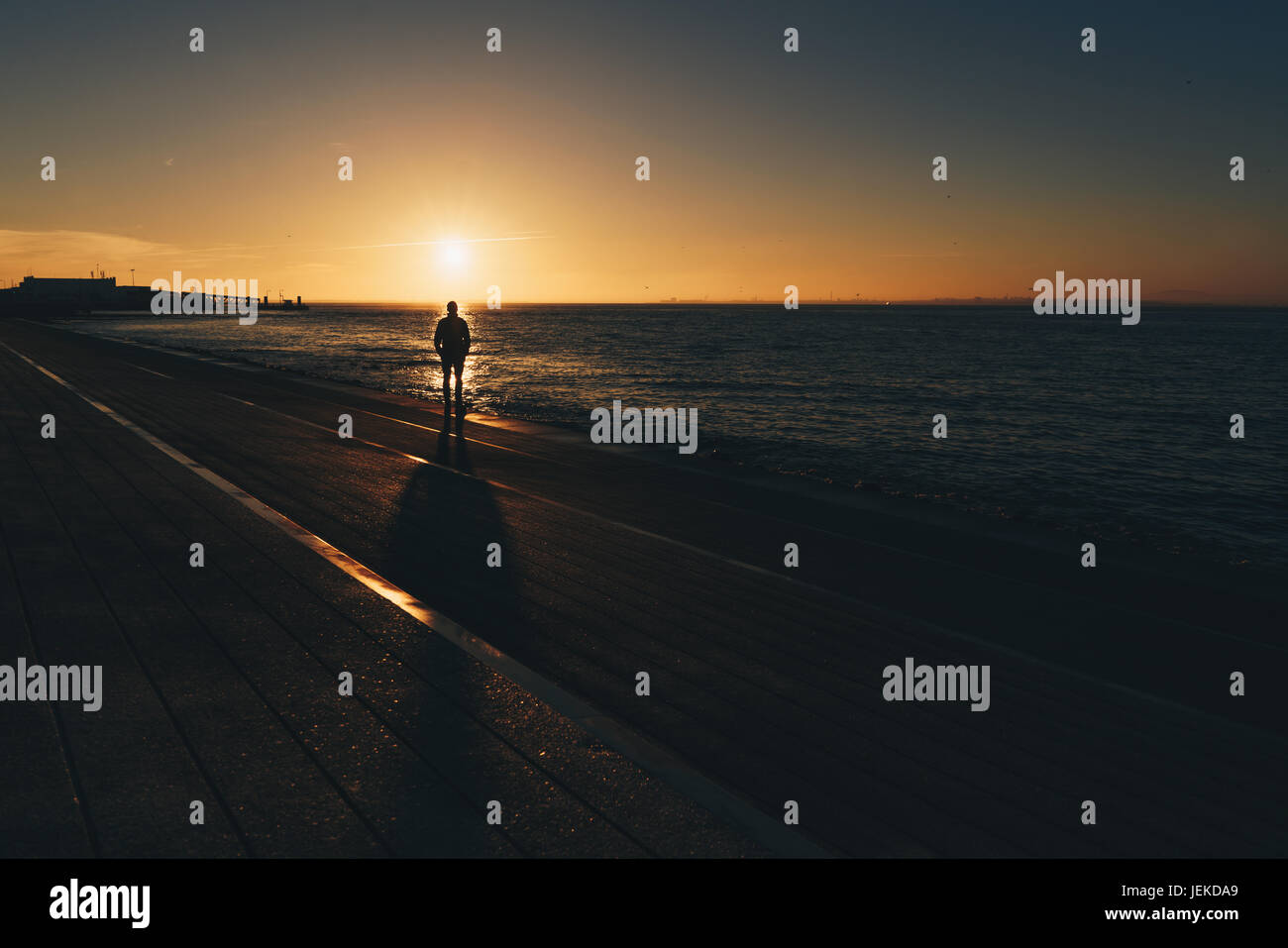 Silhouette eines Mannes stehen am Strand bei Sonnenuntergang, Lissabon, Portugal Stockfoto